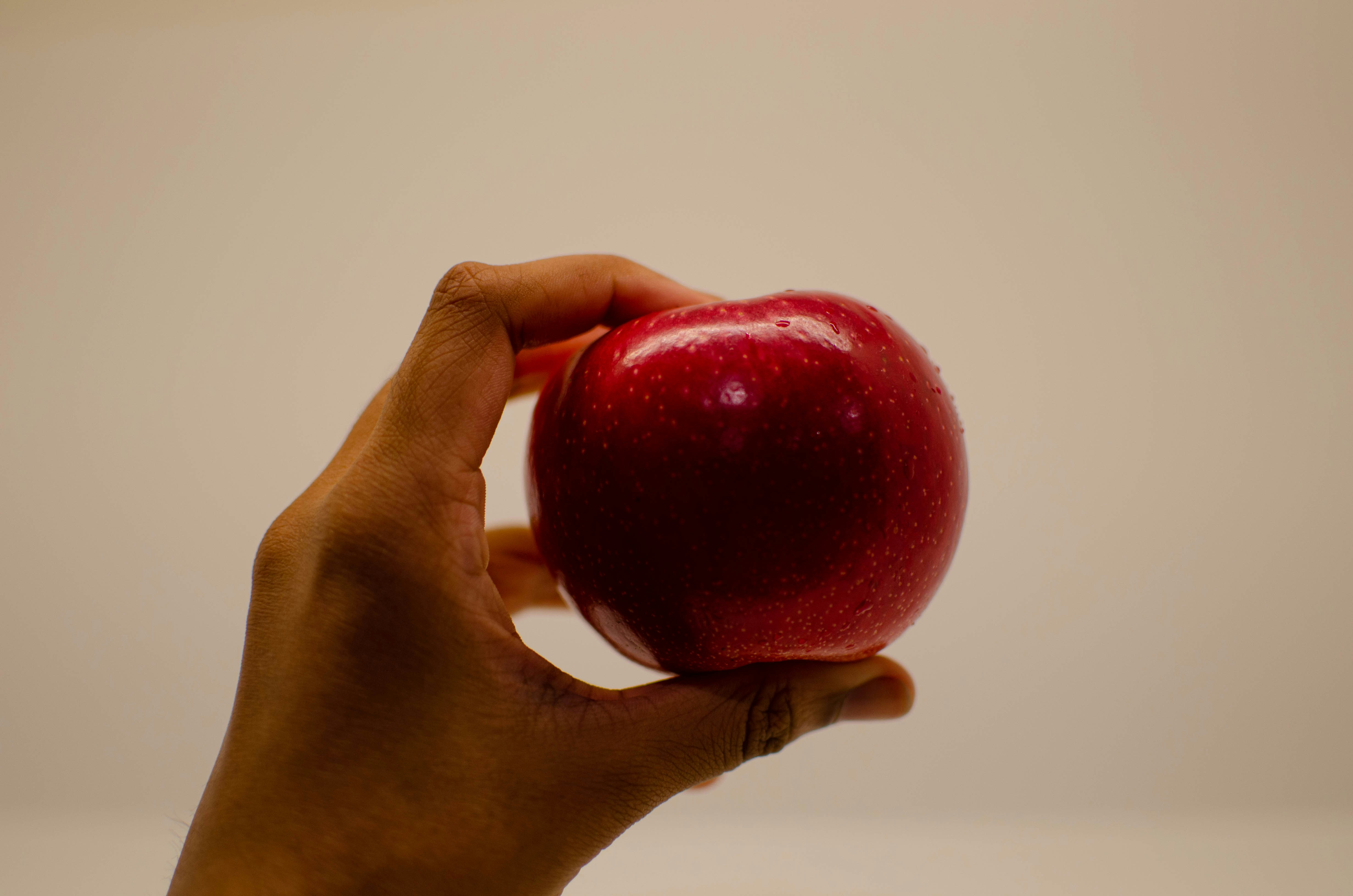 a hand holding a red apple