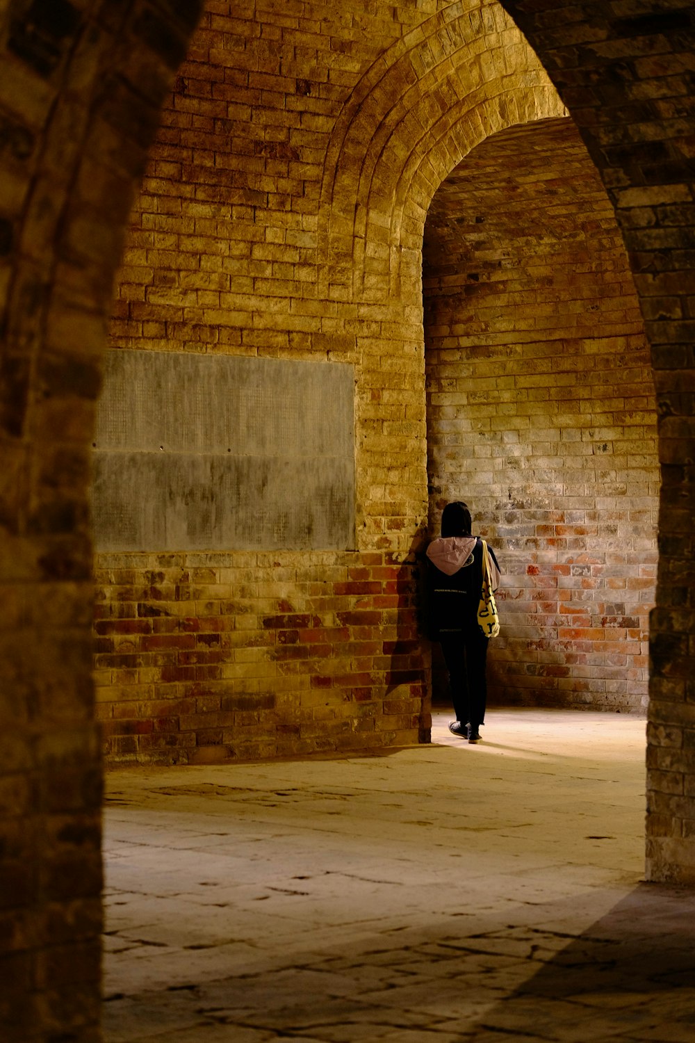 a person walking in a brick tunnel