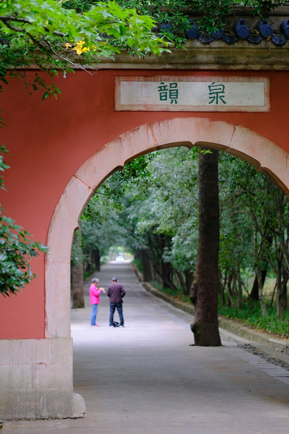 a couple of people walking under a large arch