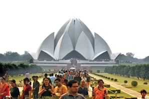 a large crowd of people in front of a large building with Lotus Temple in the background