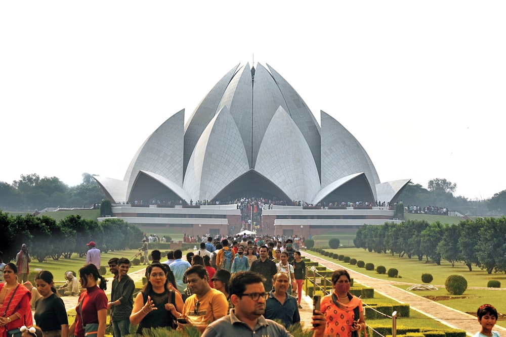 uma grande multidão de pessoas em frente a um grande edifício com o Templo de Lótus ao fundo