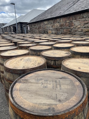 Several stainless steel barrels lined up outdoors under sunlight.