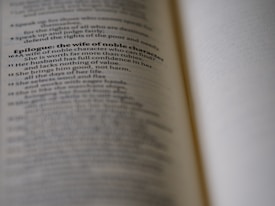 A close-up view of an open book with text discussing the qualities of a wife of noble character. The focus is on a specific passage, while the rest of the text is blurred, creating a depth of field effect.