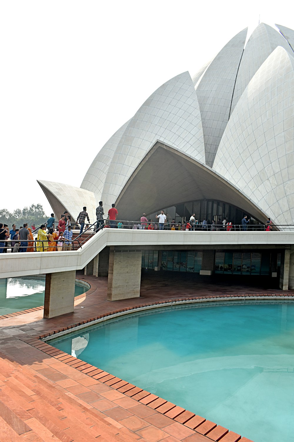 a group of people standing on a bridge over a pool