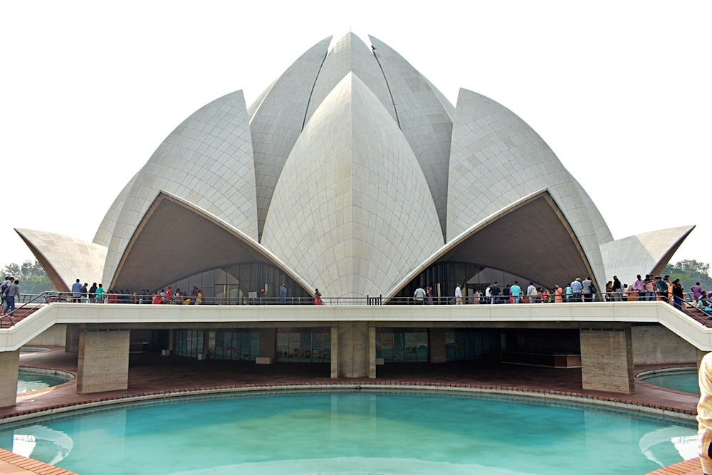 un grand bâtiment avec une piscine en face avec le temple du Lotus en arrière-plan