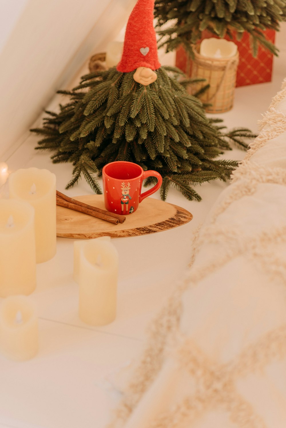 a small christmas tree with a cup of coffee and a candle on a table
