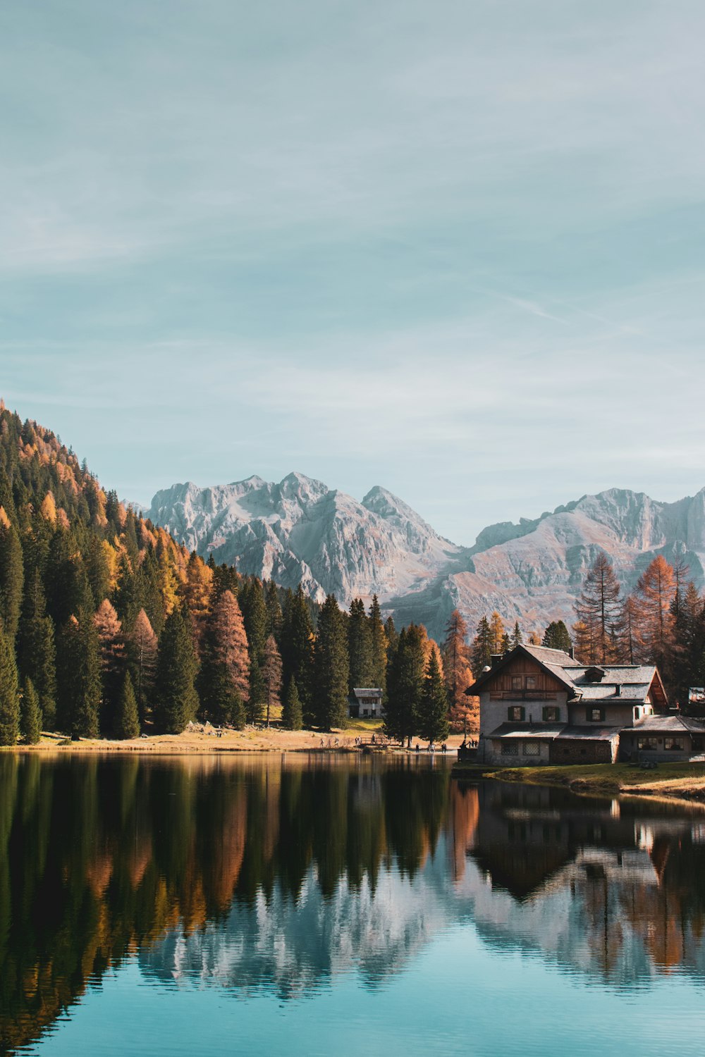 Una casa vicino a un lago con le montagne sullo sfondo