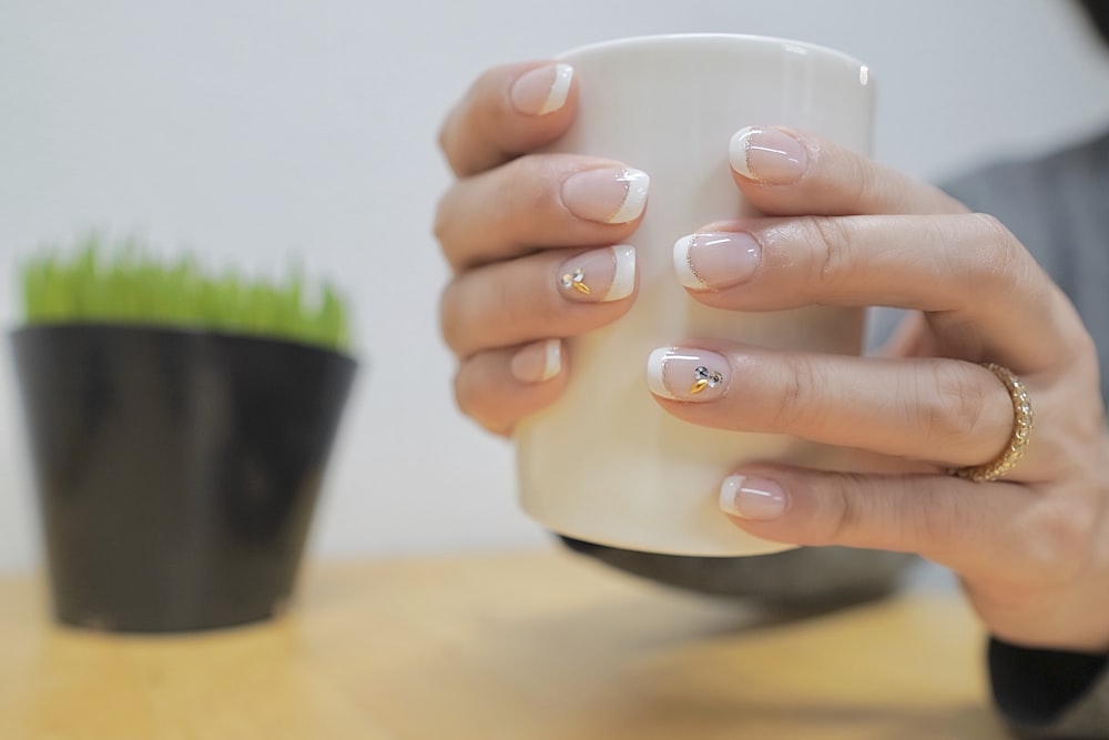 a pair of hands holding a white mug