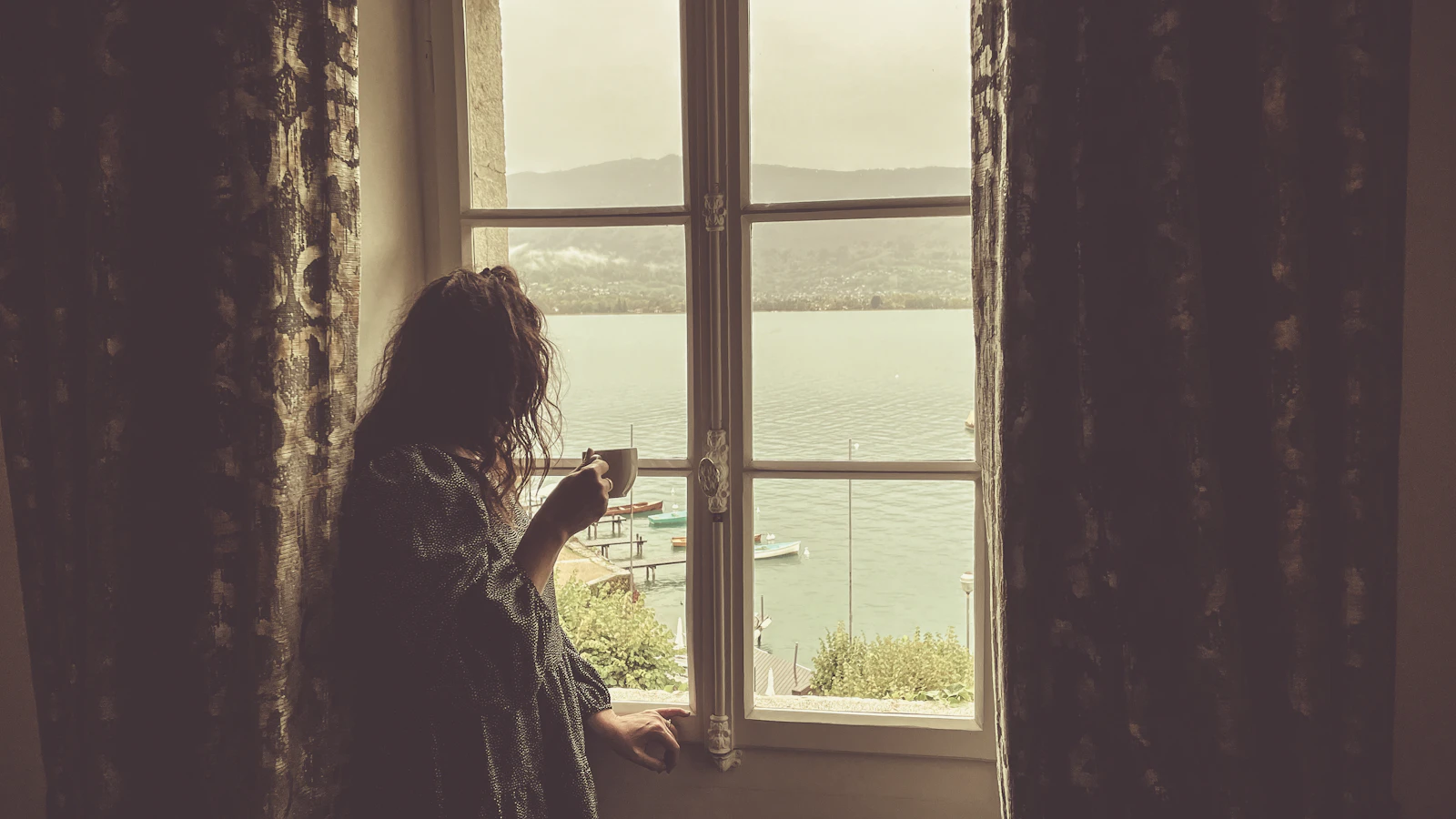 Nachdenkliche Person mit Kaffee am Fenster als Symbol für Ambivalenz beim Rauchstopp