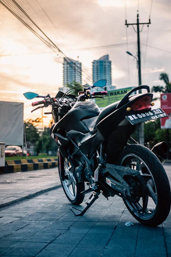 Close-up of a sleek black motorcycle parked on a city street at dusk.