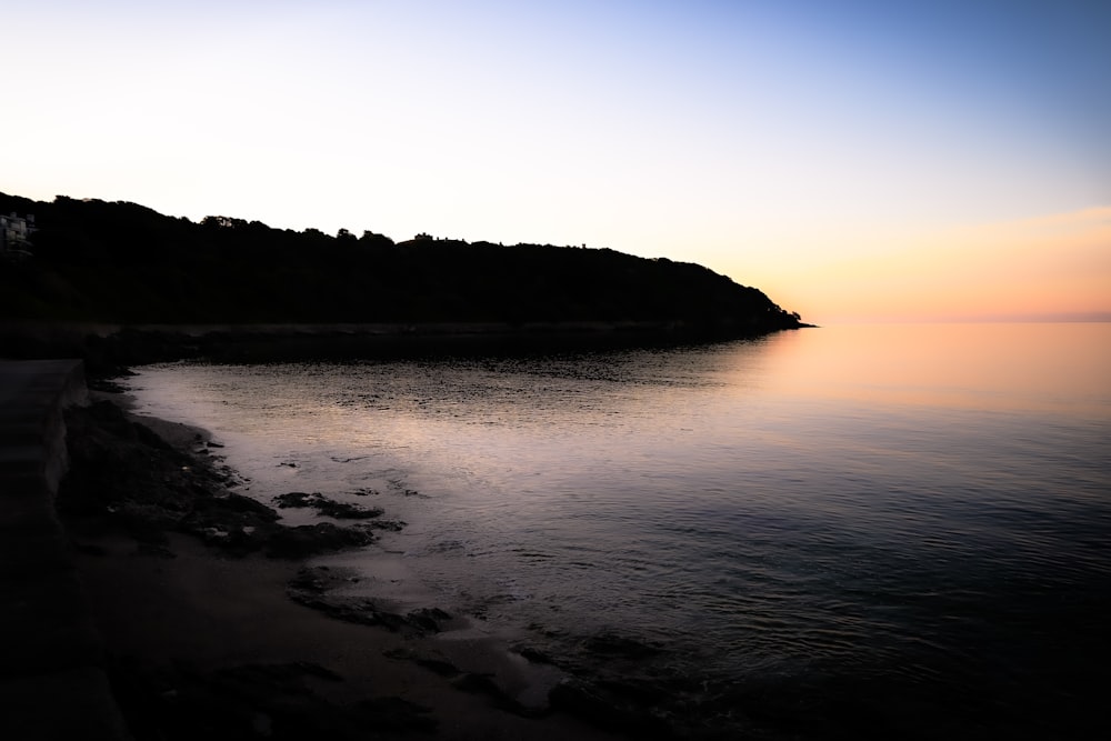 a body of water with a hill in the background