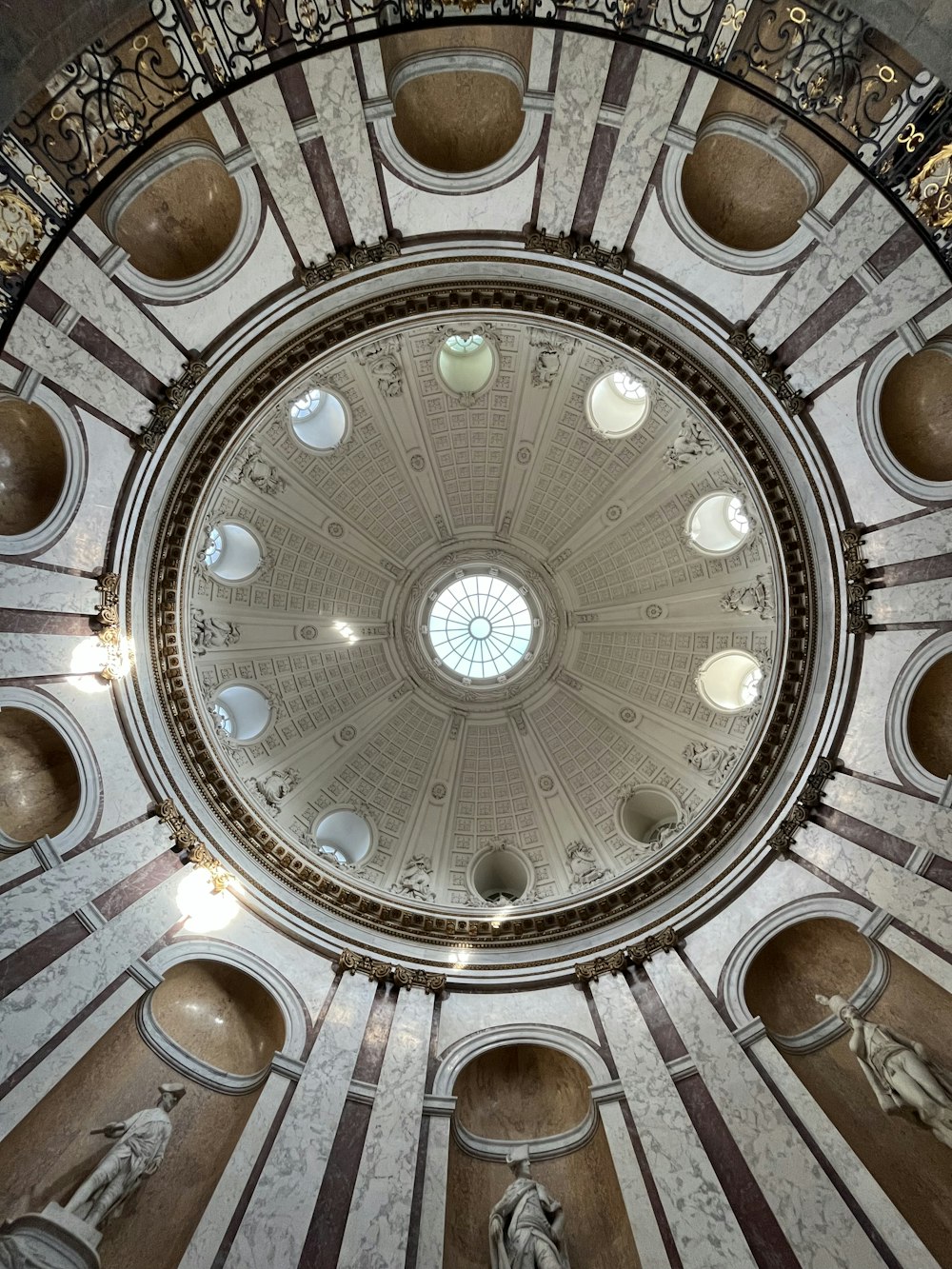 a domed ceiling with a statue with San Carlo alle Quattro Fontane in the background