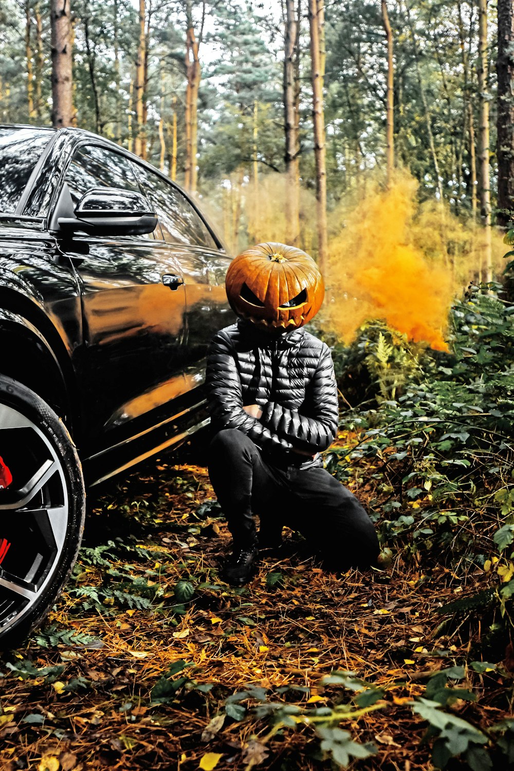 a person wearing a helmet and kneeling next to a car on fire