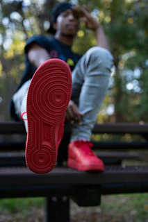 Soft-focus image of a woman sitting on a bench, showcasing crownface shoes in natural light.