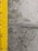 A close-up view of a concrete surface with a bright yellow painted line running vertically along the left side. The concrete appears textured with small holes and patches of discoloration, showcasing signs of wear and use.
