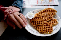 Bright and cheerful display of heart-shaped waffles topped with strawberries and syrup on a rustic wooden table.
