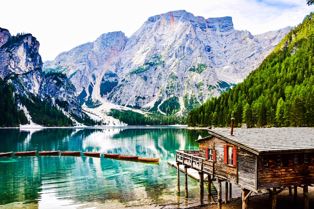 uma cabana em uma doca por um lago com montanhas ao fundo