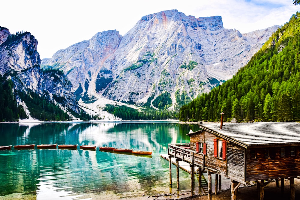 a cabin on a dock by a lake with mountains in the background