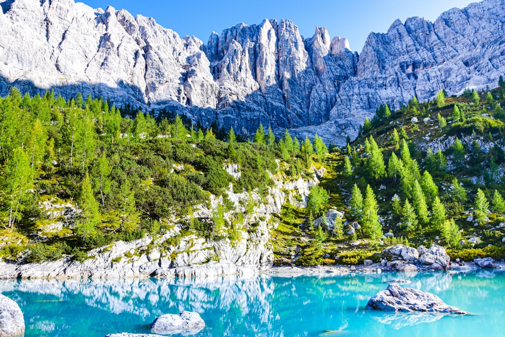 a body of water with trees and mountains in the background with Dolomites in the background