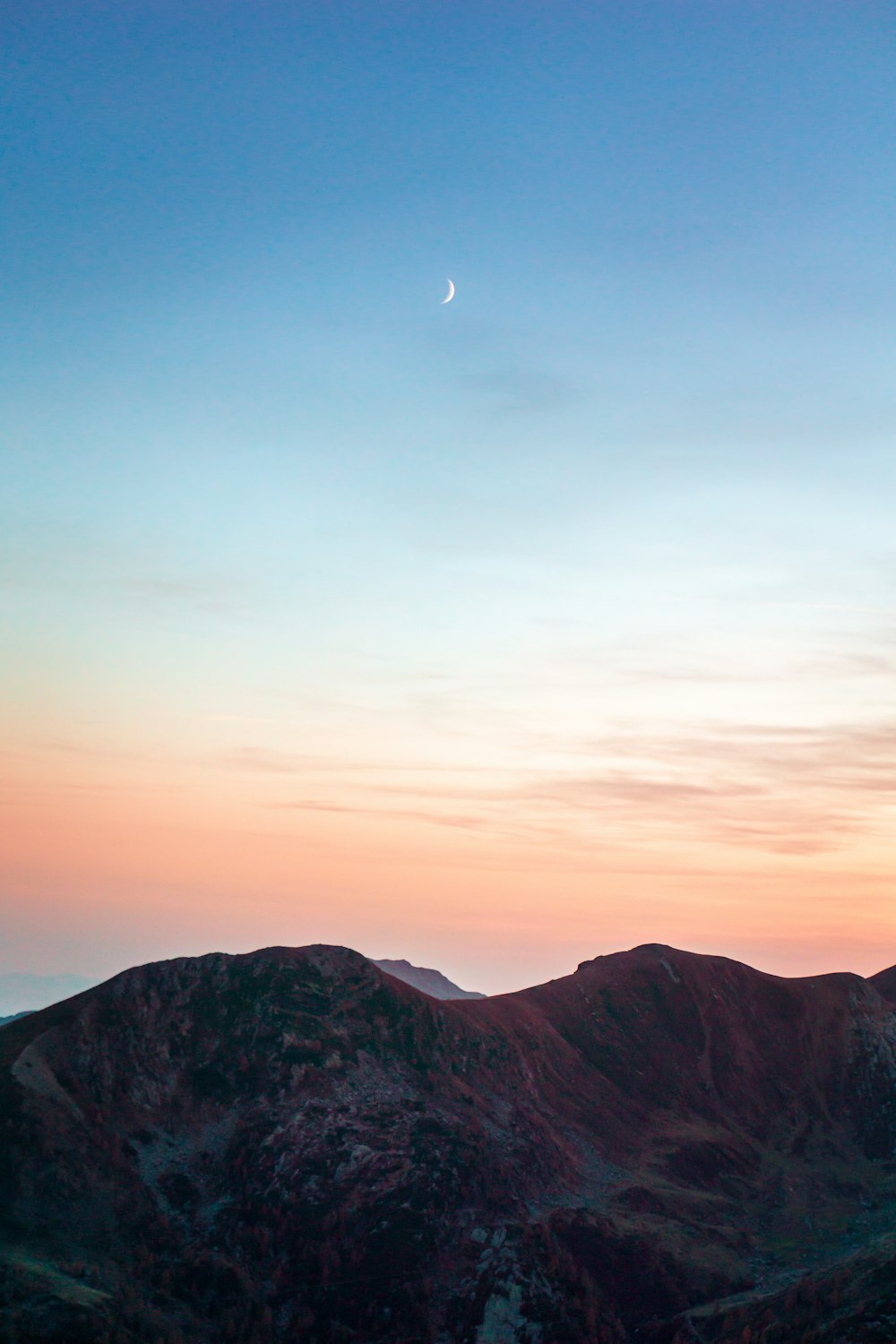 a mountain with a moon in the sky