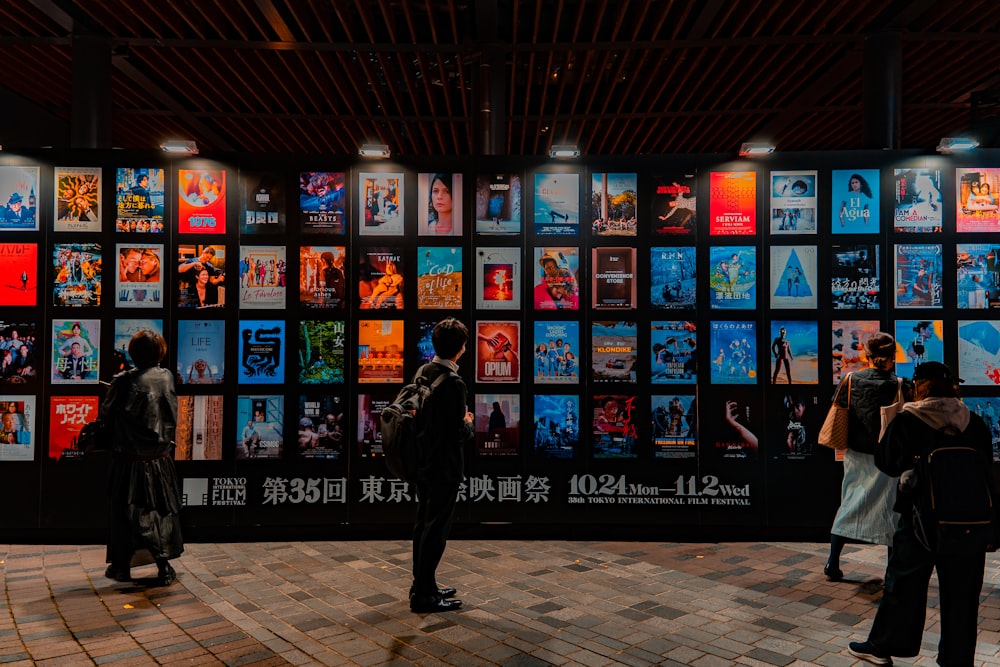 people standing in front of a wall of pictures