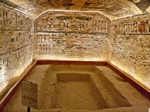 Team of researchers documenting findings inside a dimly lit tomb chamber