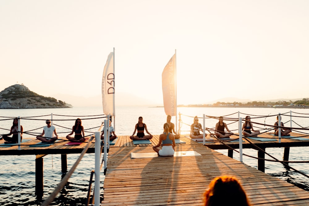 a group of people sitting on a dock by the water