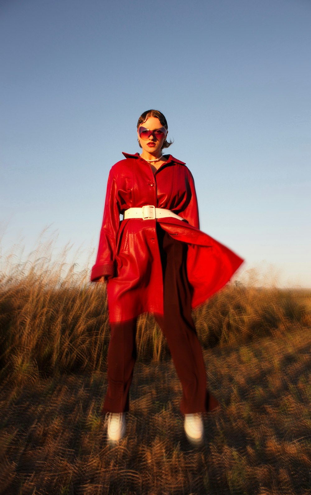 a man wearing a red suit and sunglasses standing in a grassy area