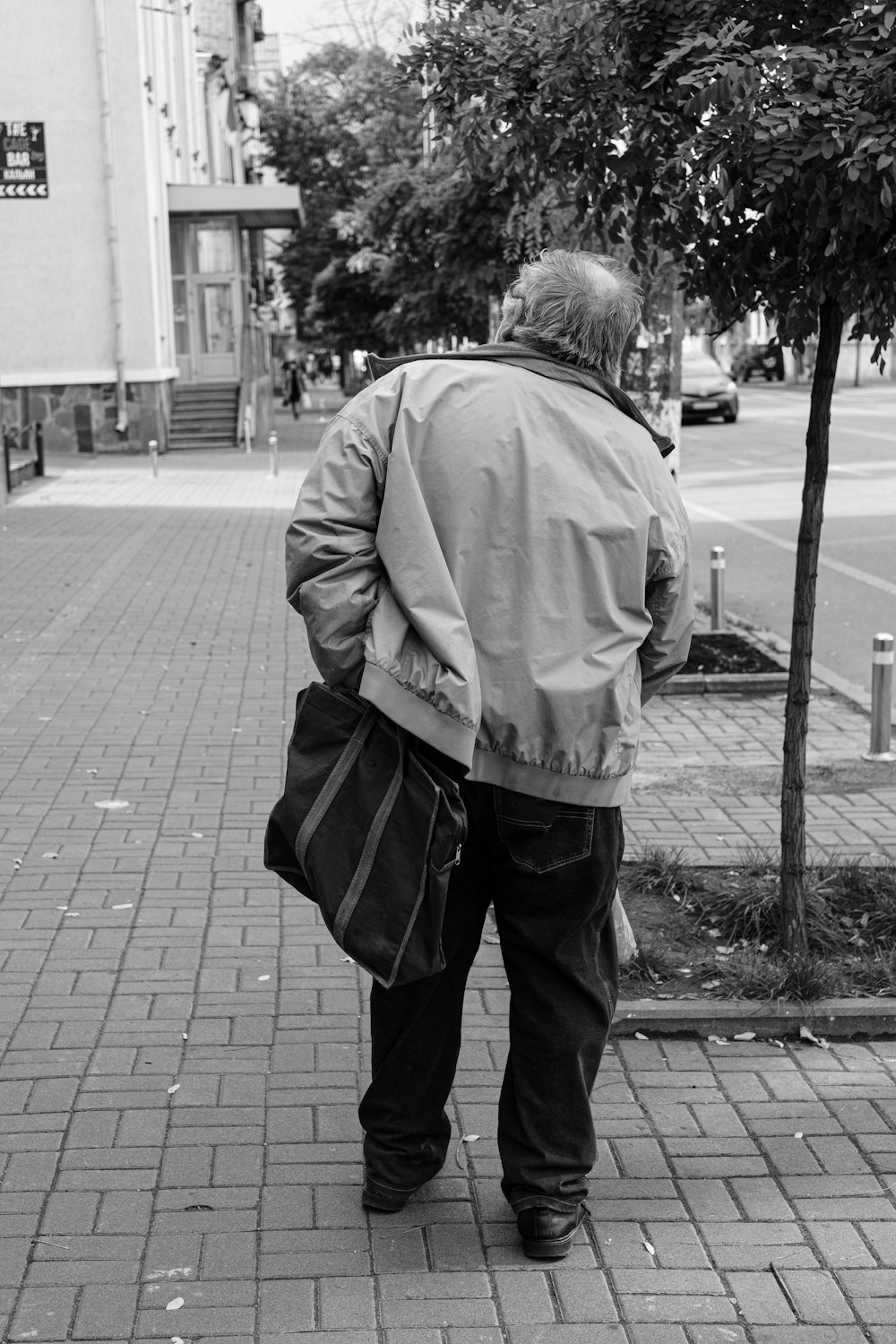 a person with a bag walking down a sidewalk