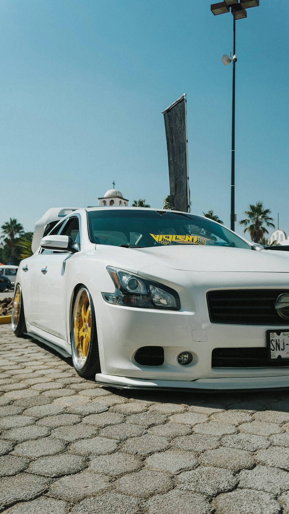 um carro branco estacionado em uma estrada de tijolos