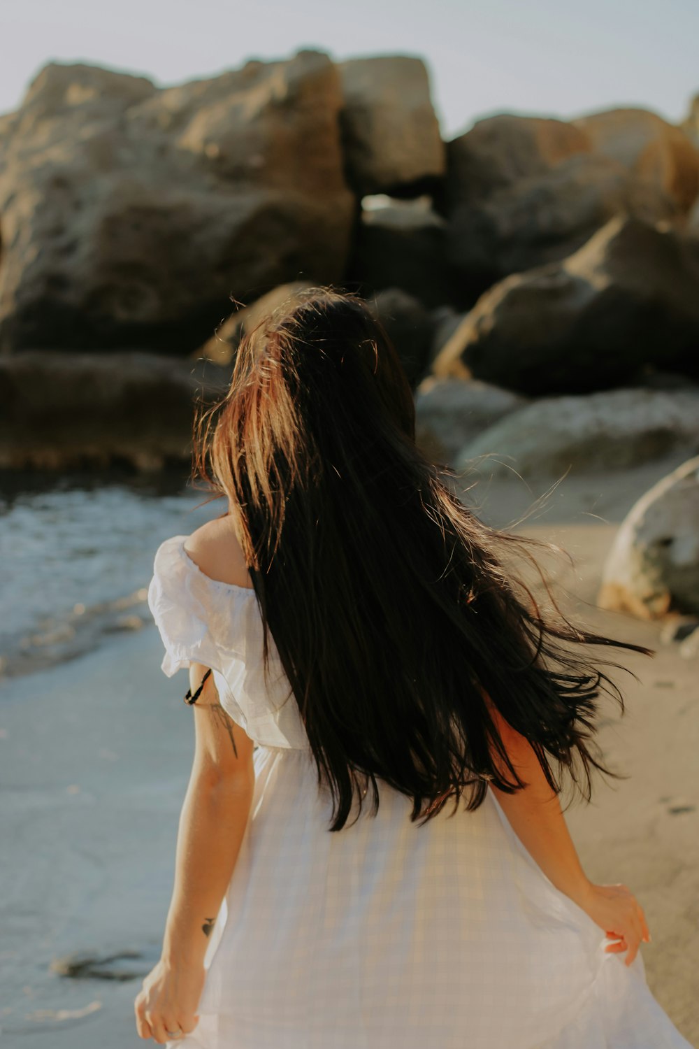 a woman with her hair blowing in the wind on a beach