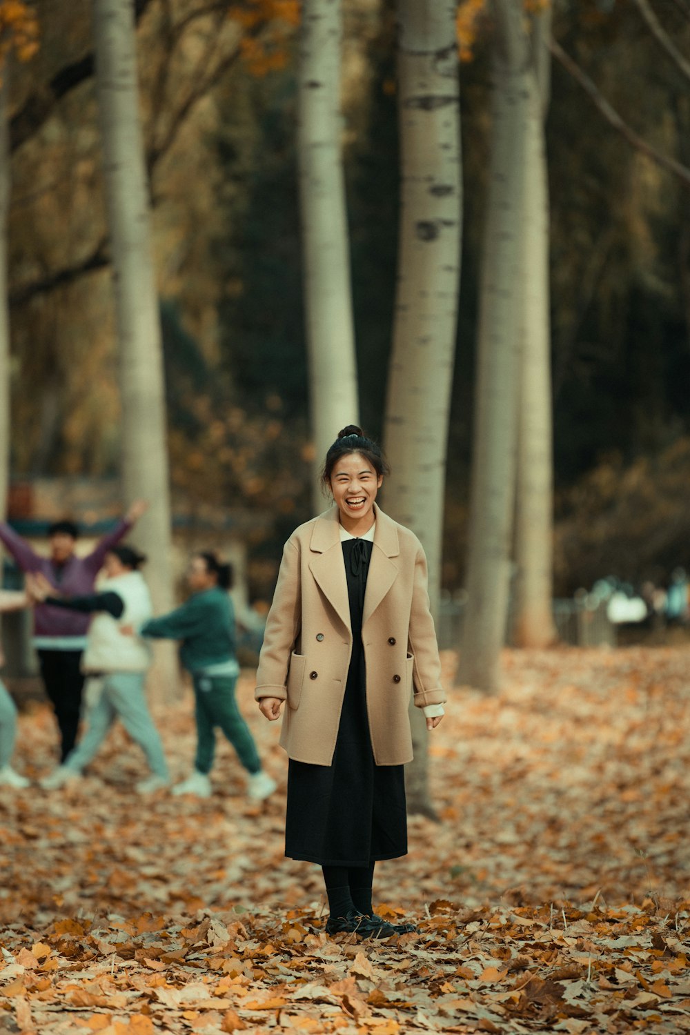 a person in a trench coat standing in a forest