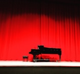 A grand piano bathed in soft stage lighting during a live performance.