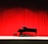 Image of a grand piano on stage with soft spotlight