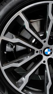 Close-up of a sleek BMW alloy wheel featuring a glossy M Sport sticker under natural sunlight.