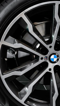 Close-up of a sleek BMW alloy wheel featuring a glossy M Sport sticker under natural sunlight.