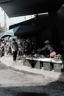 A vibrant outdoor market scene in Vietnam with caps displayed under natural sunlight.