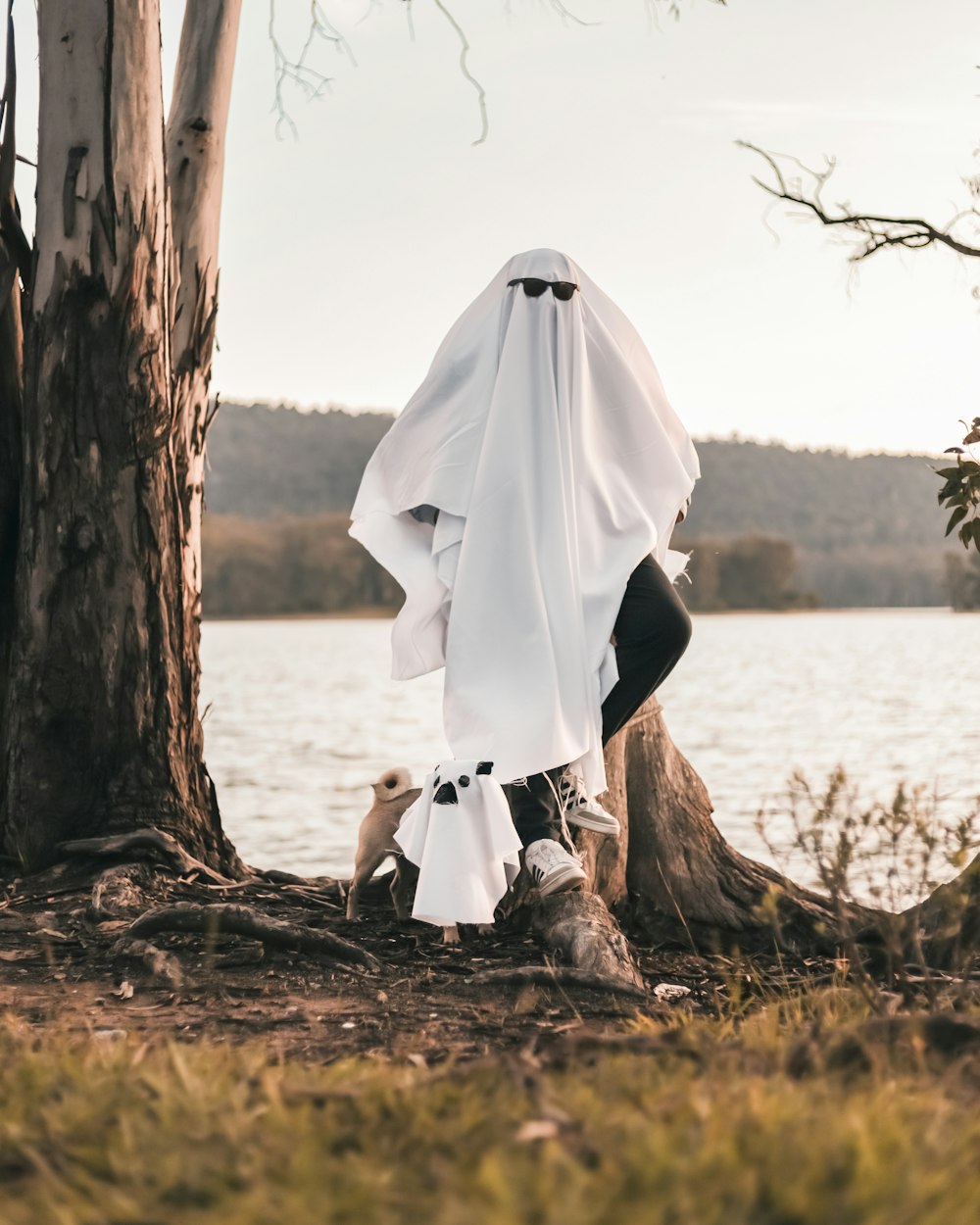 a person in a white shirt and black pants leaning against a tree