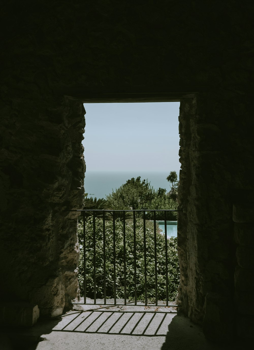 a stone doorway with a fence and trees in the background