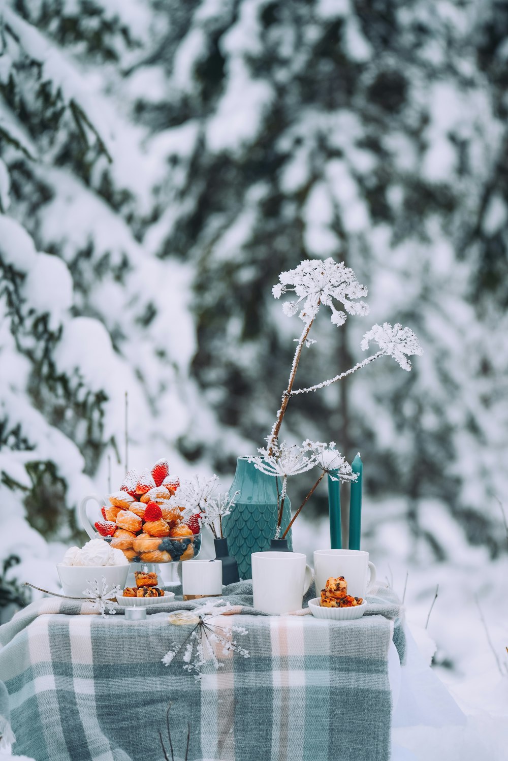 a table with food and drinks on it with snow on the side
