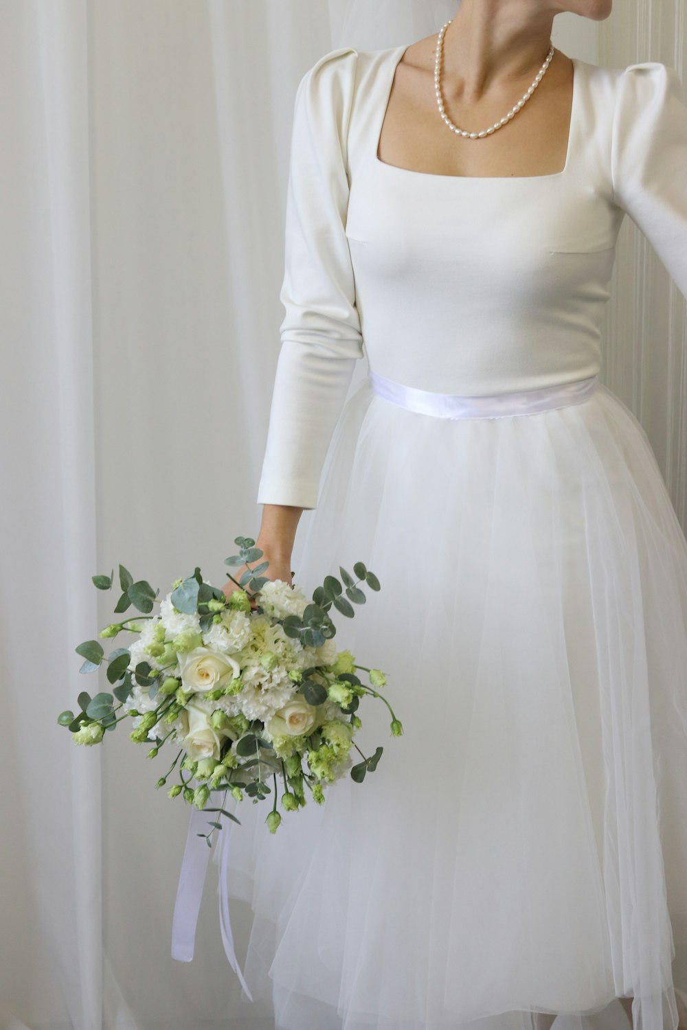 a woman wearing a white dress holding a bouquet of flowers