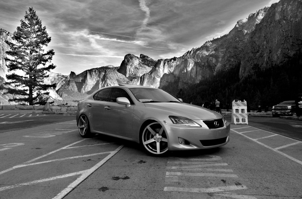 a silver car parked in a parking lot with mountains in the background