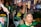 A group of people is gathered, one holding a megaphone and others wearing green, yellow, and blue clothing, indicative of support for Brazil. Flags, banners, and patriotic colors are prominent amid an urban nighttime setting. One person is singing or speaking passionately with a microphone.