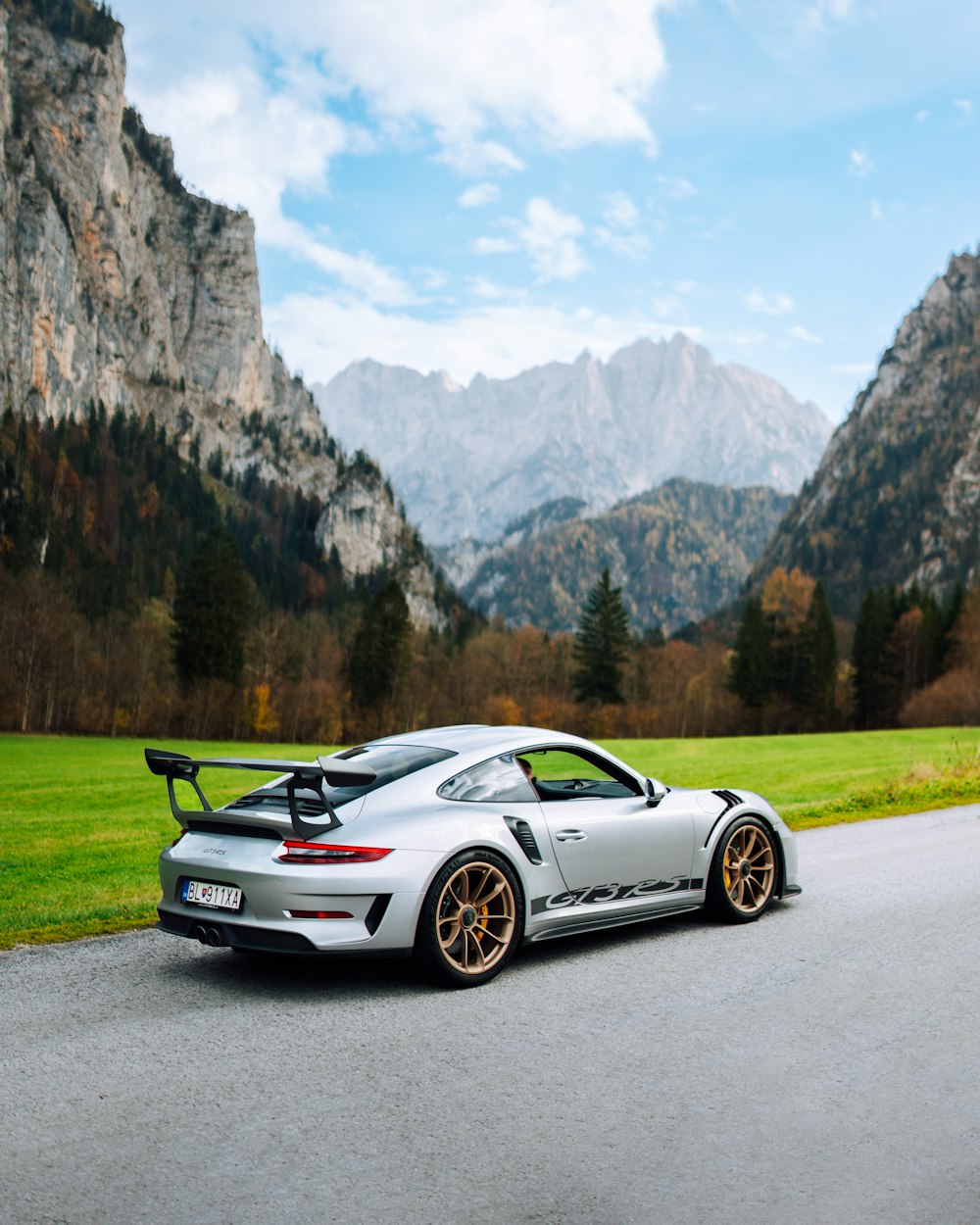 a sports car parked on a road with mountains in the background