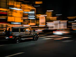 A black SUV cruising through the illuminated streets of downtown Chicago at night.