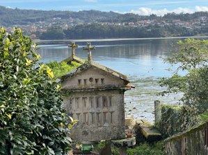 a building with a cross on top by a body of water