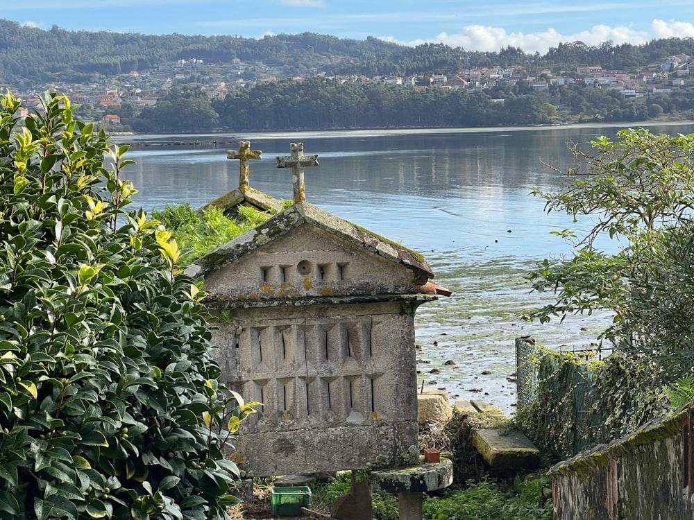 a building with a cross on top by a body of water