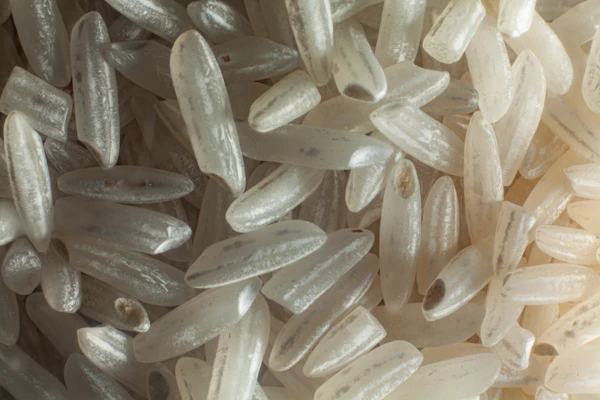 Close-up of fluffy, polished Sona Masoori Raw Rice grains spilling from a burlap sack.