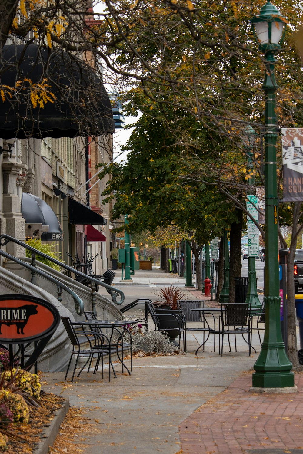 a sidewalk with tables and chairs