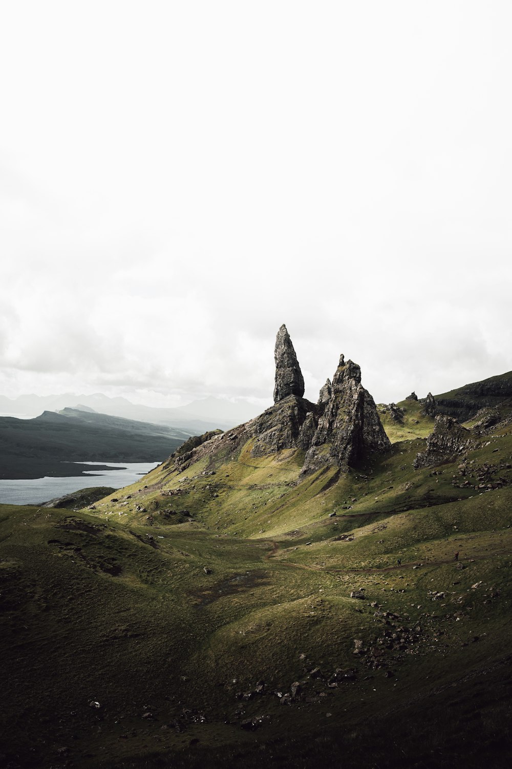 a rocky mountain with a body of water in the background with The Storr in the background